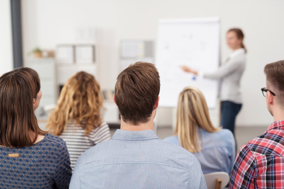 Rear View of Young Office Workers in Casual Outfits Listening to a Top Manager Explaining Something Using Illustrations.-3